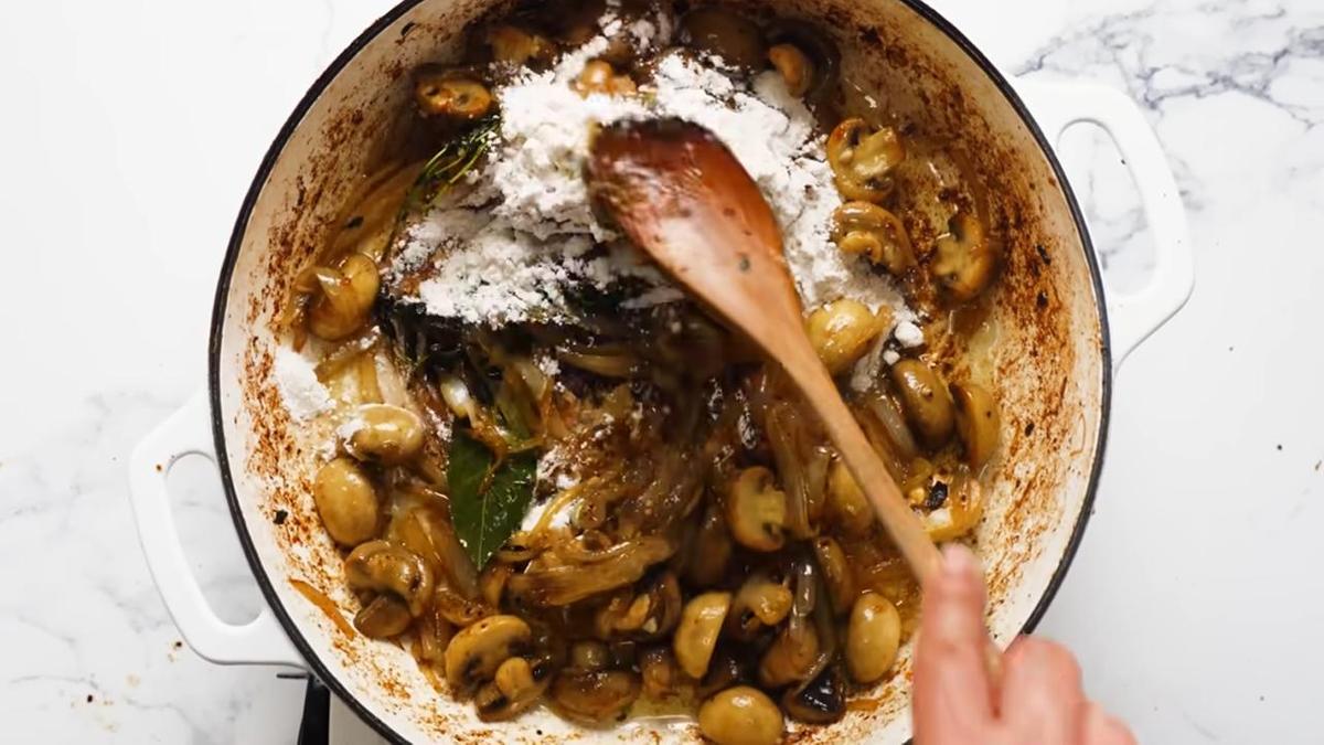 В сковороде перемешивают грибы и лук с мукой