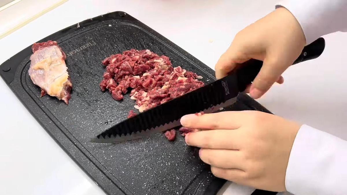 На разделочной доске нарезают баранину мелким кубиком