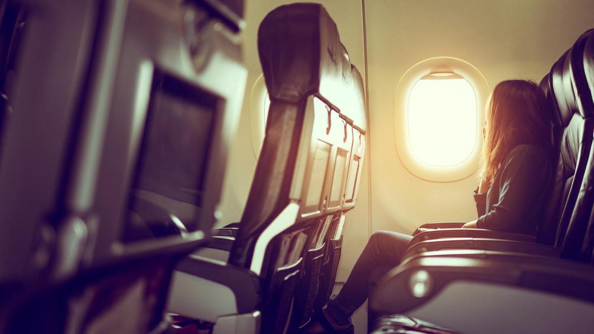 Девушка сидит в самолете на месте у окна Девушка сидит в самолете на месте у окна