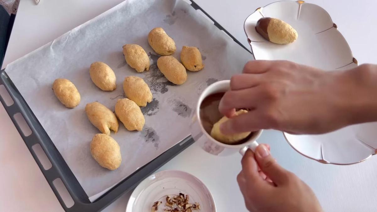 Песочное печенье окунают в пиалу с растопленным шоколадом