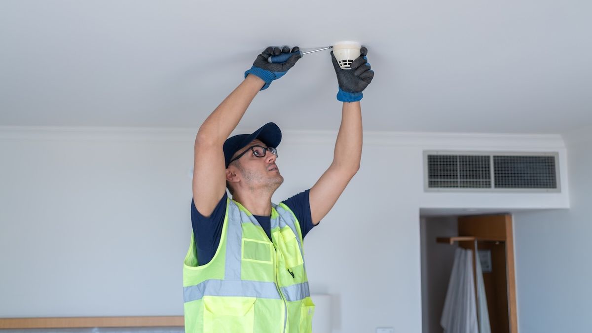 Мастер устанавливает датчик дыма