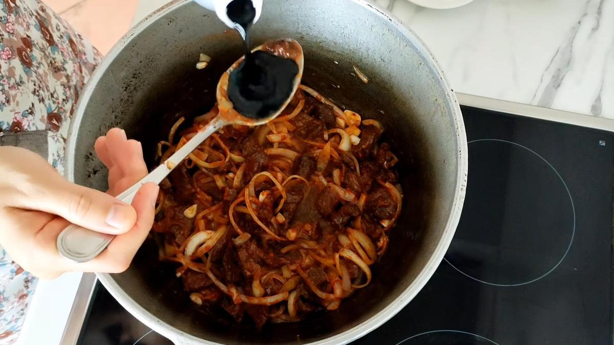 Добавление соевого соуса в казан с мясом