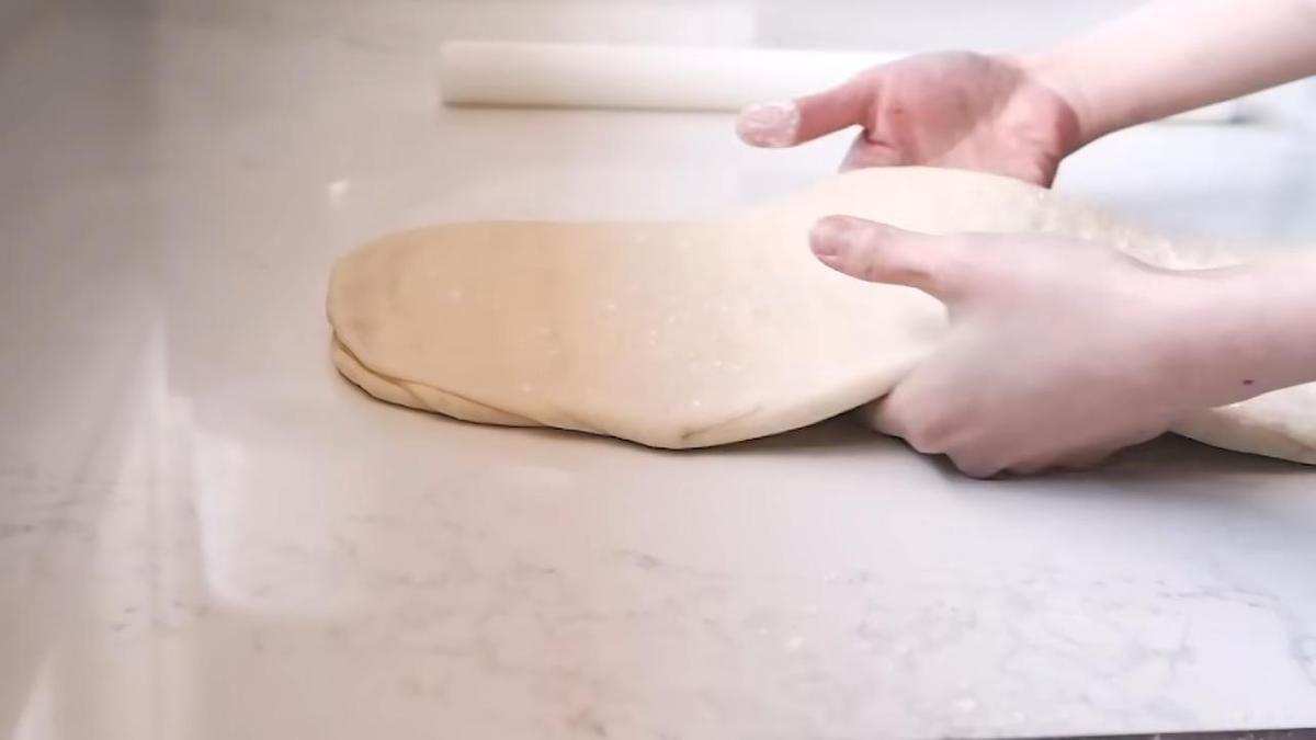Пласт слоеного теста в руках