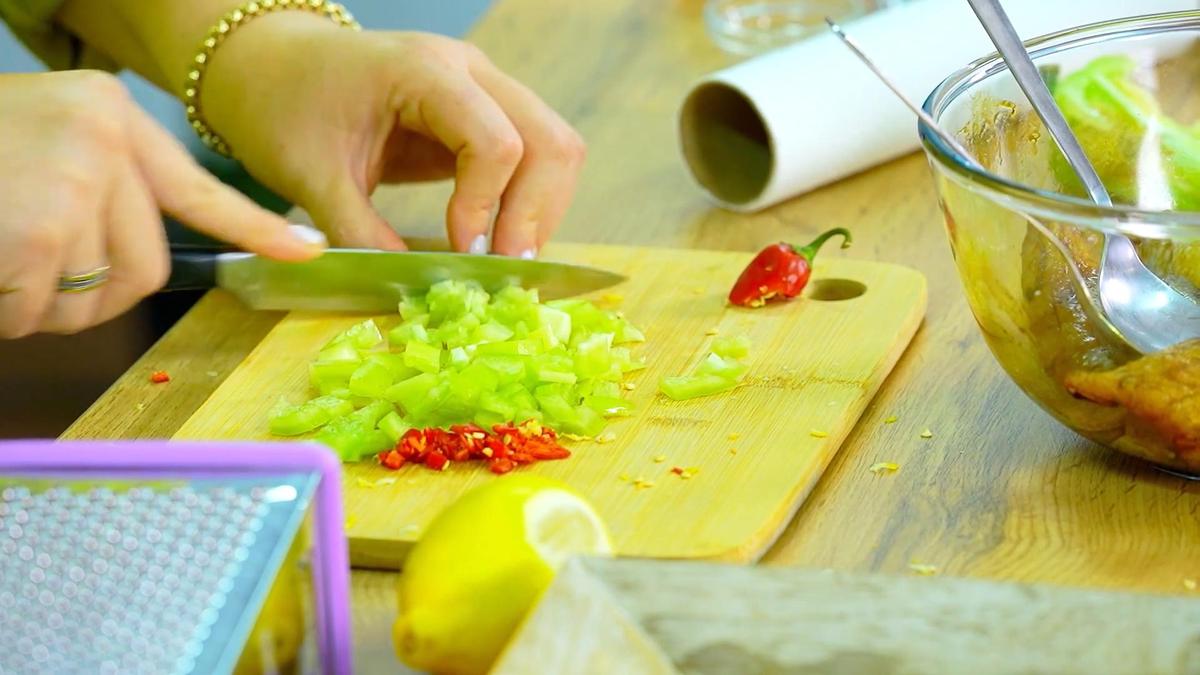 Сладкий перец и перец чили нарезают на разделочной доске