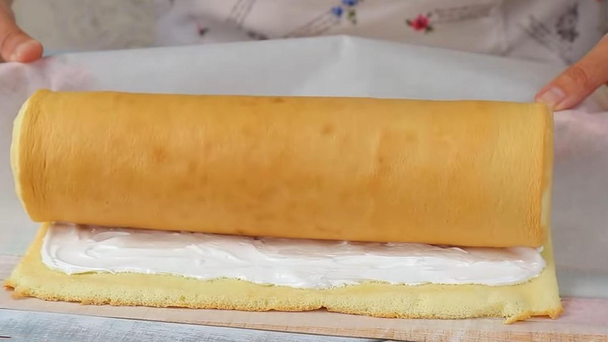 Бисквитный корж, смазанный кремом, сворачивают в рулет