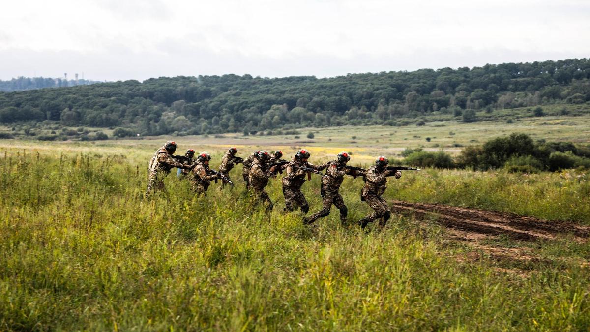 Военные с оружием идут по полю