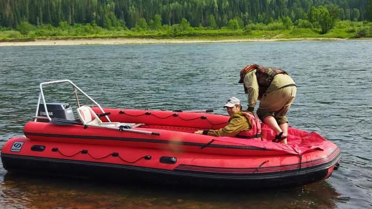 Двое мужчин в красной моторной лодке