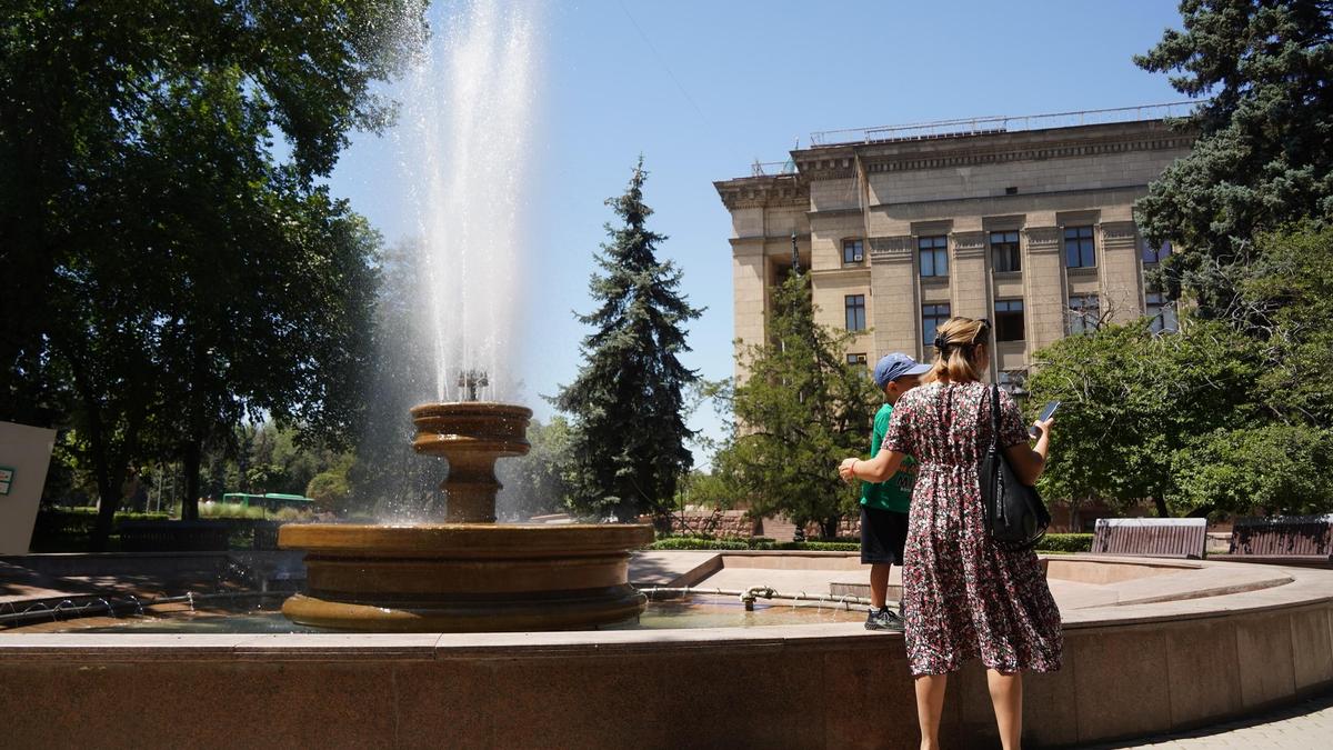 Женщина и мальчик возле фонтана в жаркий день