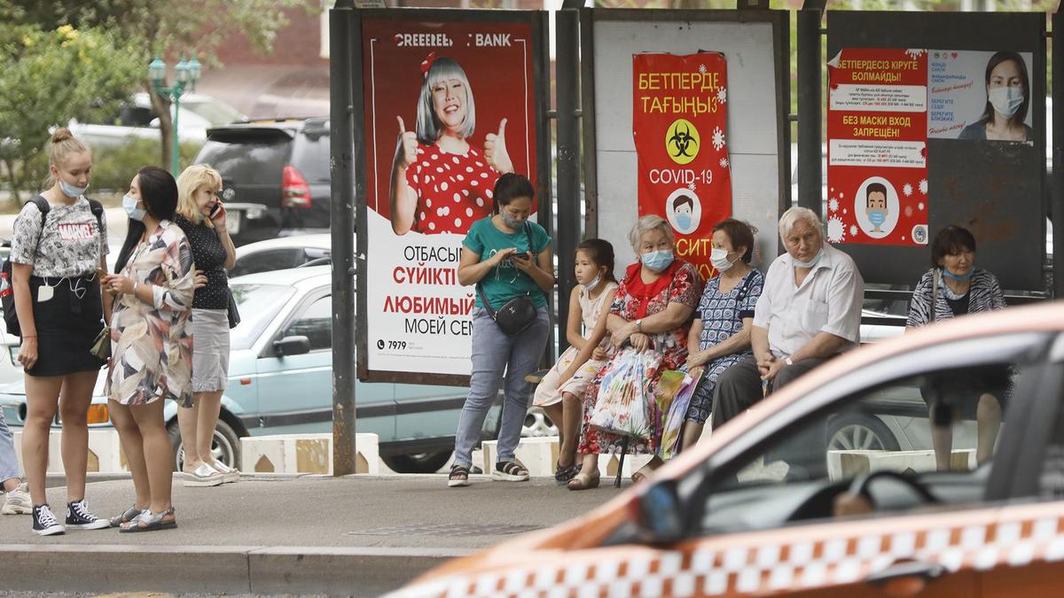 Люди стоят на остановке в Алматы