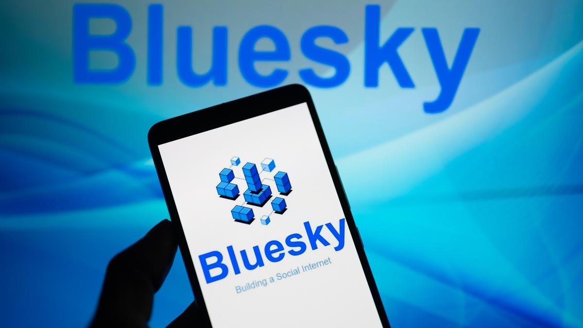 Человек держит смартфон с логотипом Bluesky