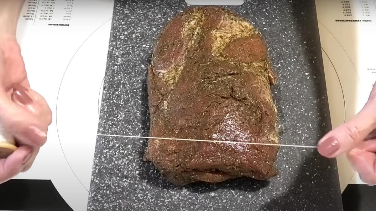 Заготовку буженины перематывают бечевкой