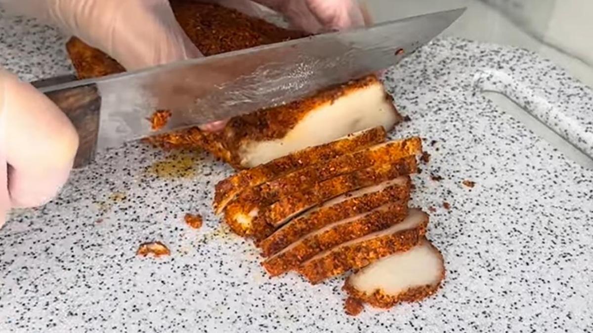 На разделочной доске нарезают сало на ломтики