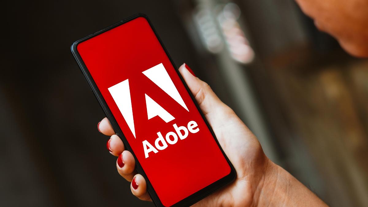 Мужчина держит в руках смартфон в логотипом Adobe