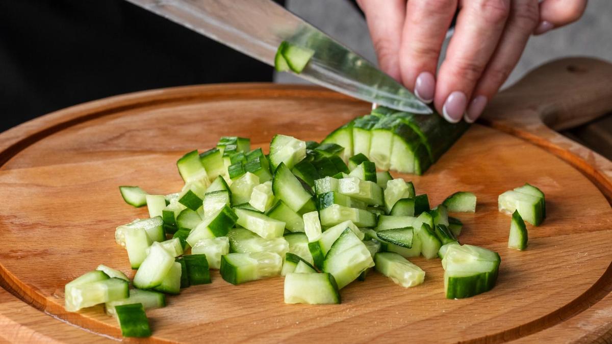 Нарезка свежего огурца на разделочной доске
