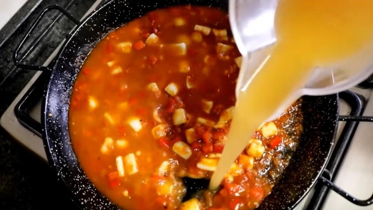 Рыбный бульон наливают в сковороду с кальмаром и овощами