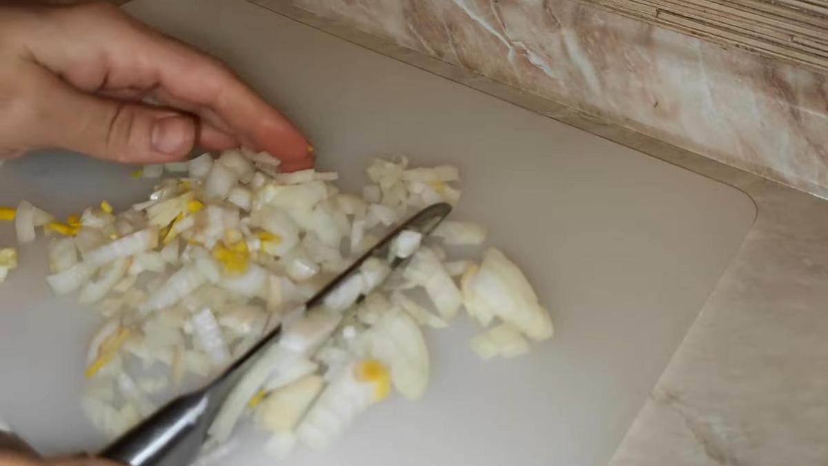 Нарезанный мелким кубиком лук на разделочной доске
