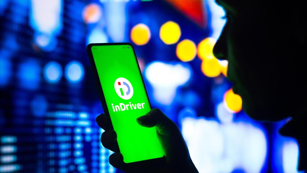 Мужчина смотрит приложение inDriver на смартфоне