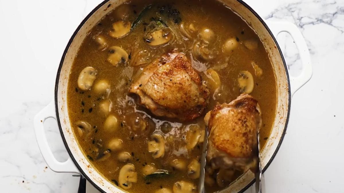 В сковороду с овощами и бульонов щипцами кладут курицу