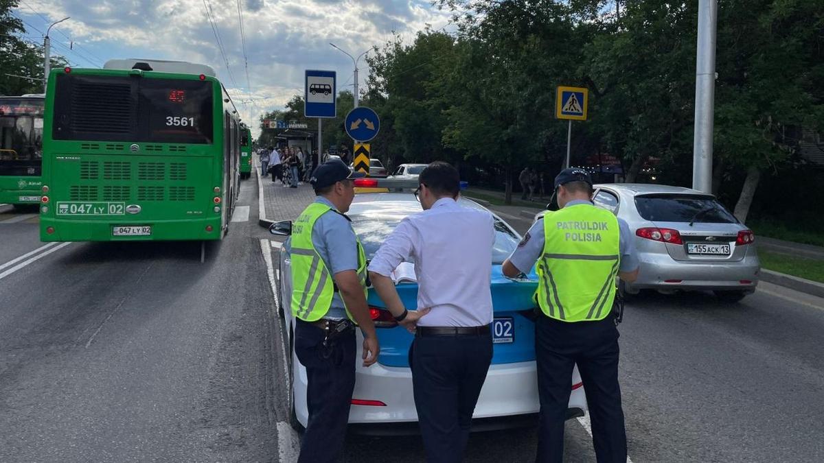 Мужчина и двое полицейских стоят у служебного авто