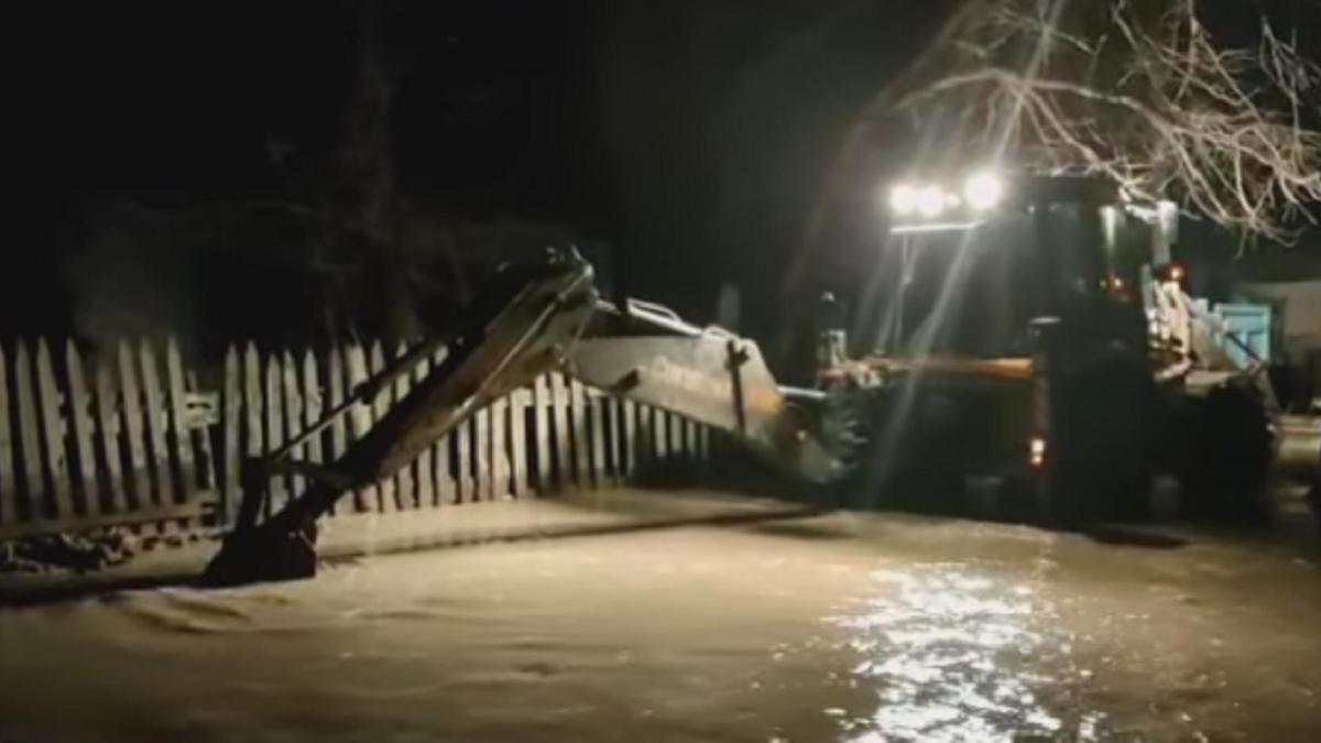 Су басқан аулада жұмыс істеп жатқан техника Су басқан аулада жұмыс істеп жатқан техника