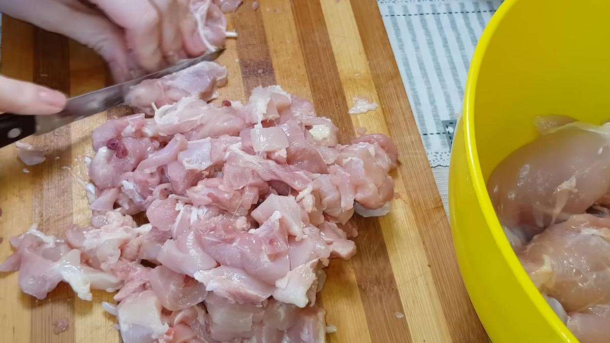 На разделочной доске кубиком нарезают куриное мясо