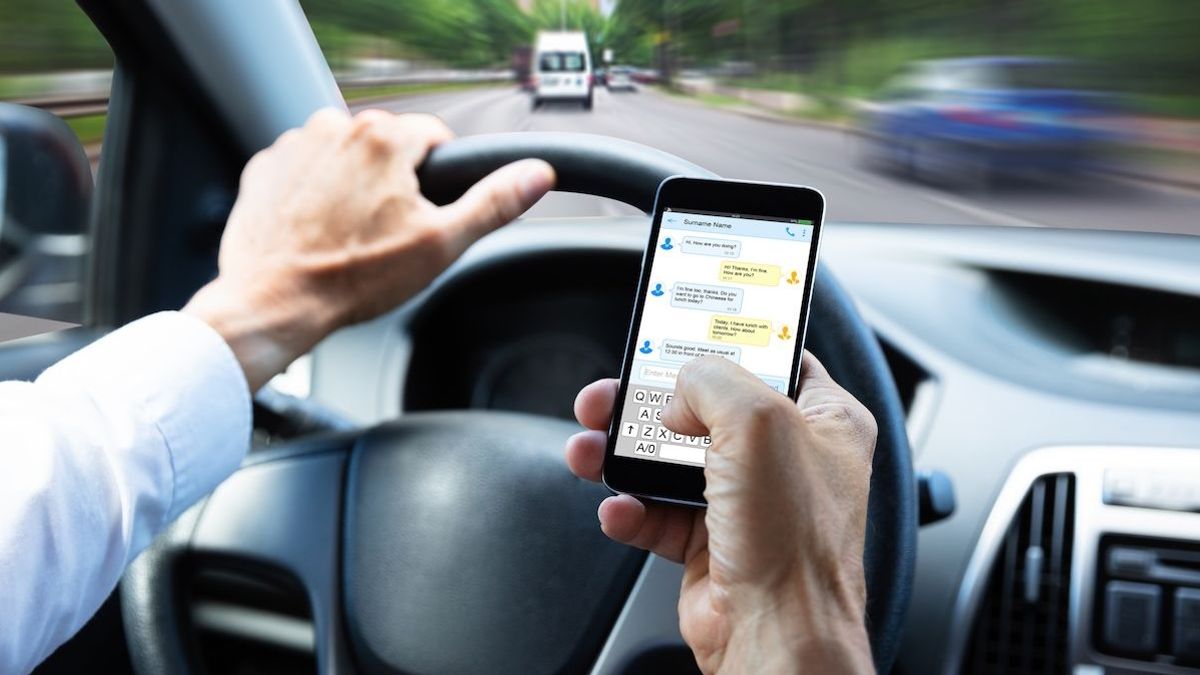 Водитель переписывается по смартфону в движении