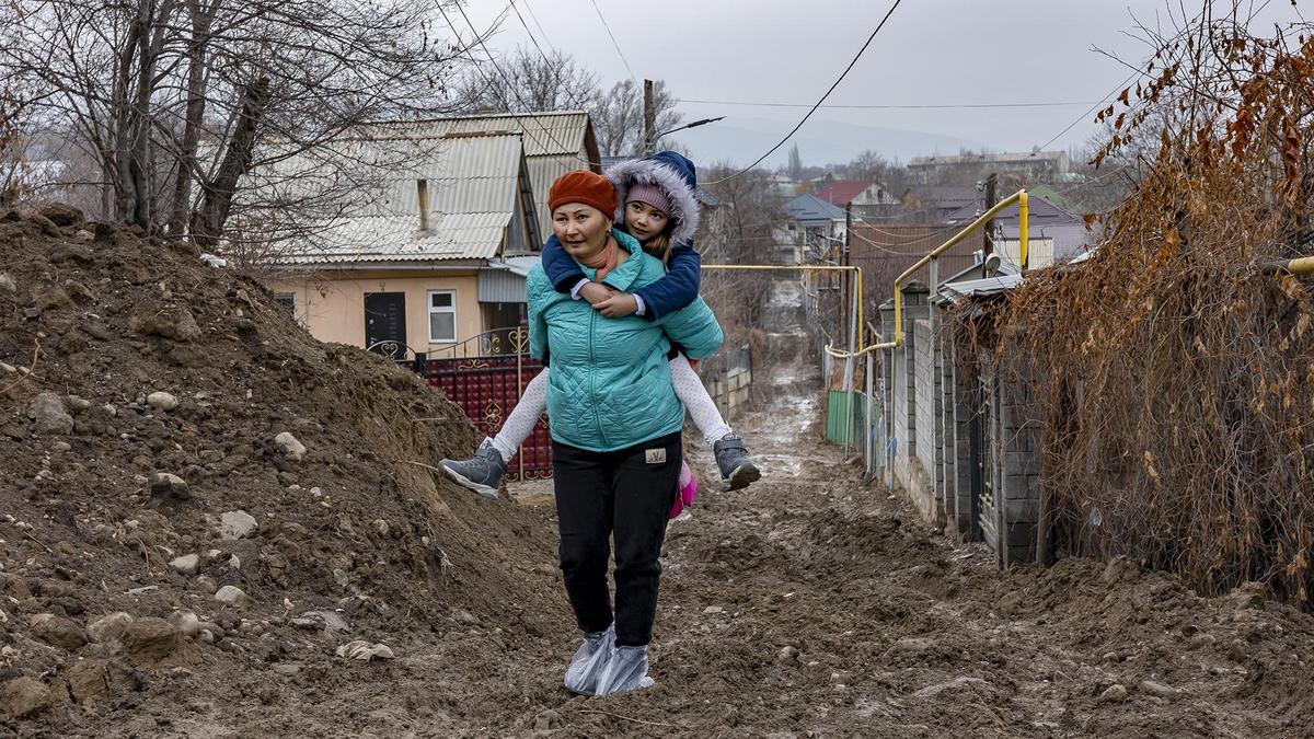 Женщина несет ребенка на спине