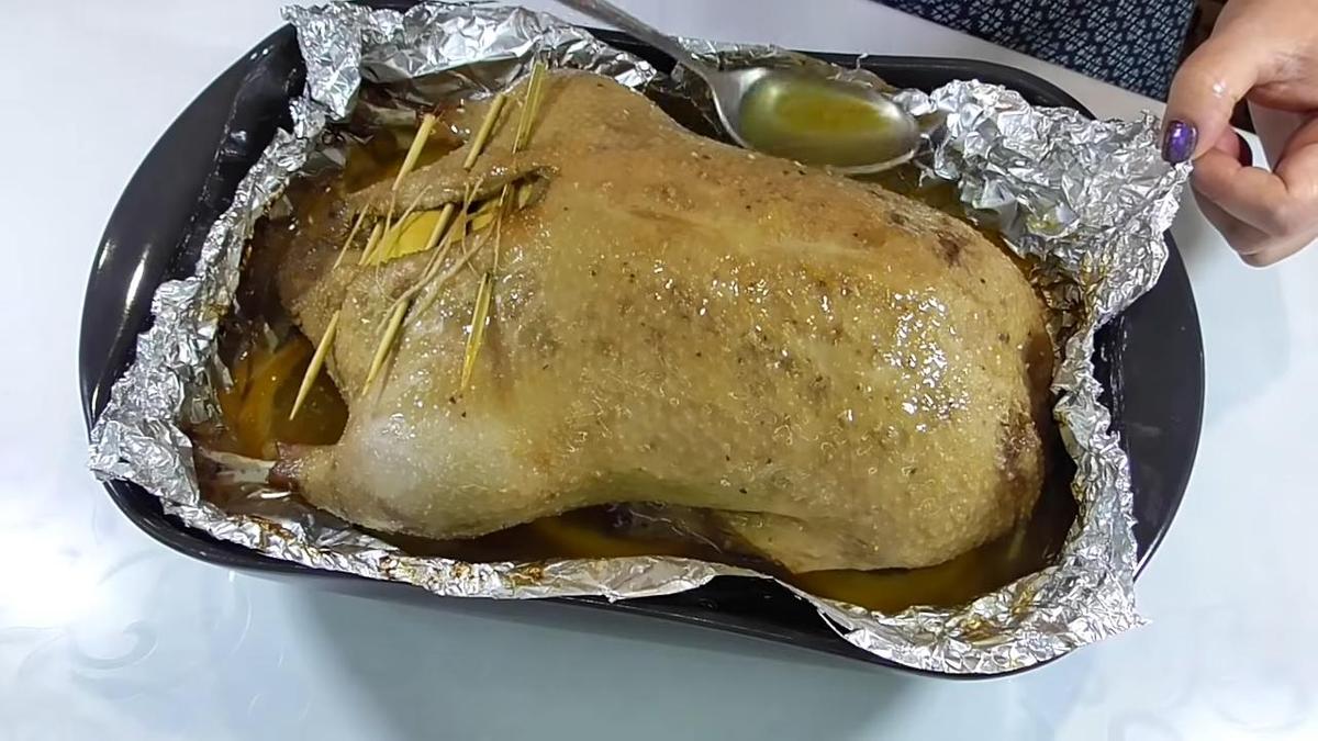 Утку в форме для выпекания поливают жиром, образовавшимся во время запекания