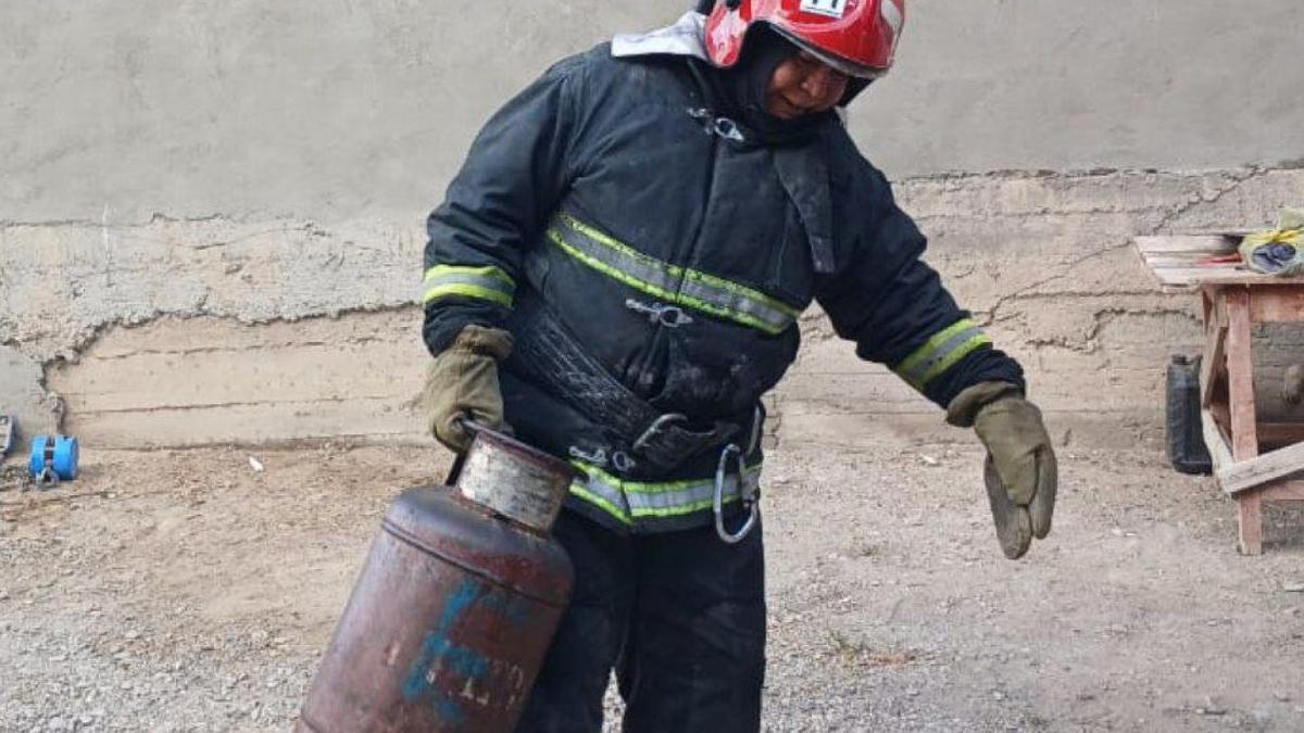 Пожарный несет газовый баллон