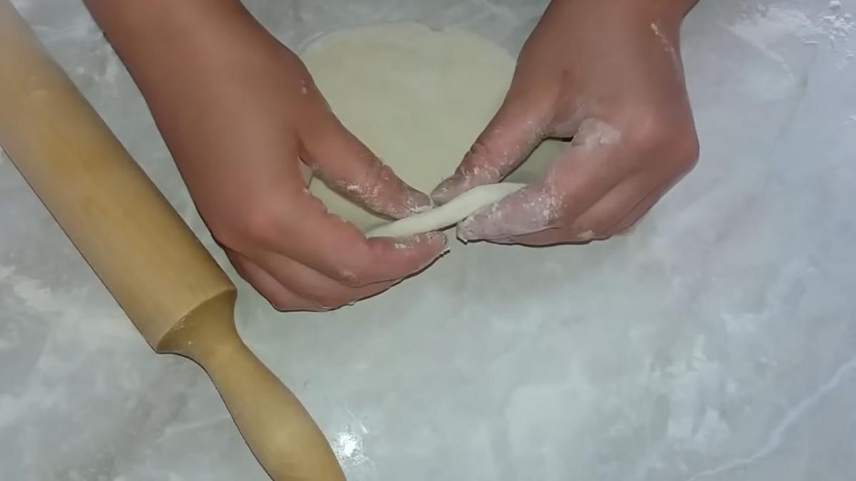 В руках раскатанное тесто. Рядом скалка