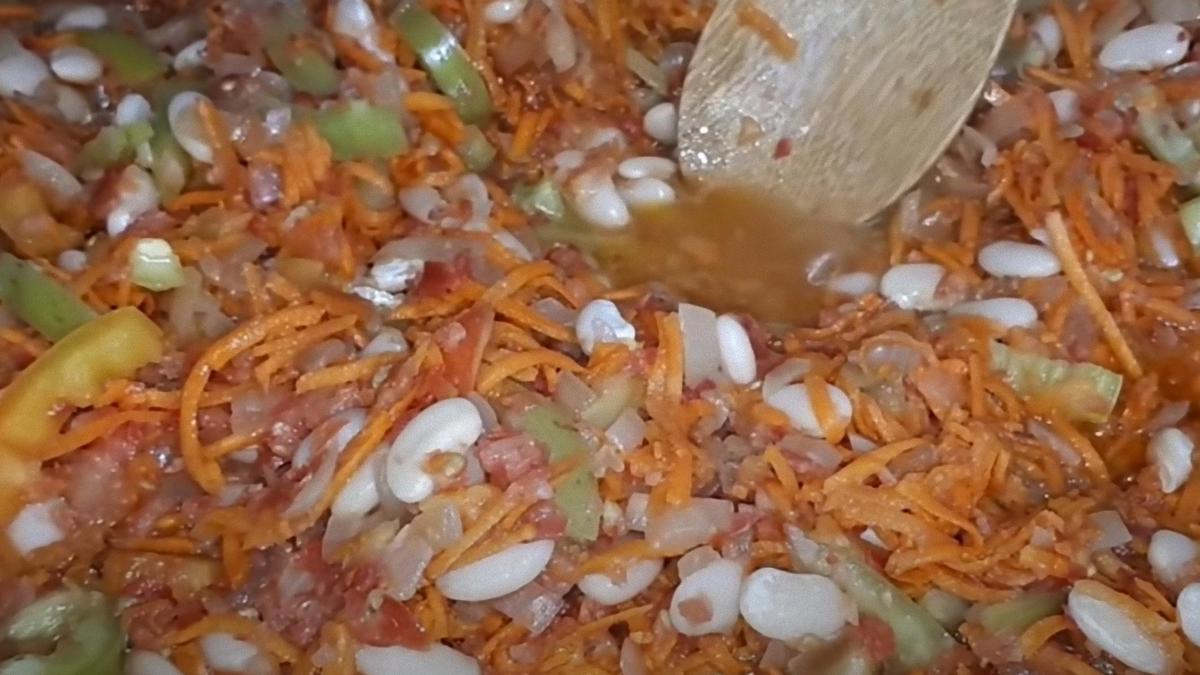 Фасоль с овощами мешают лопаткой