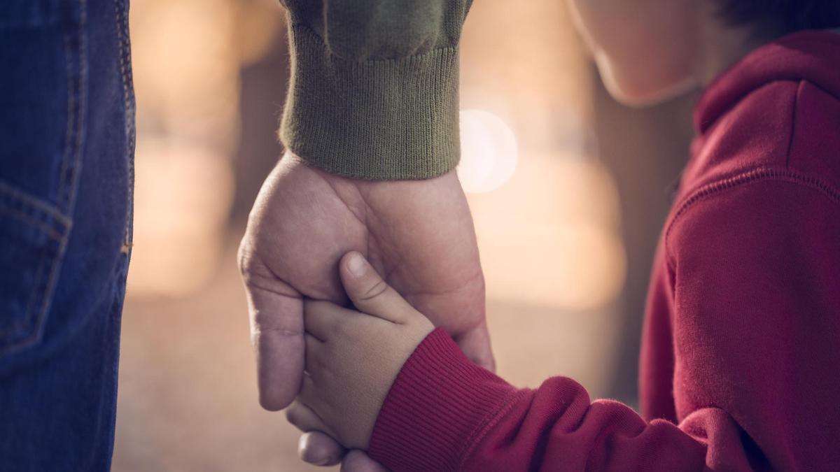 Мужчина держит мальчика за руку