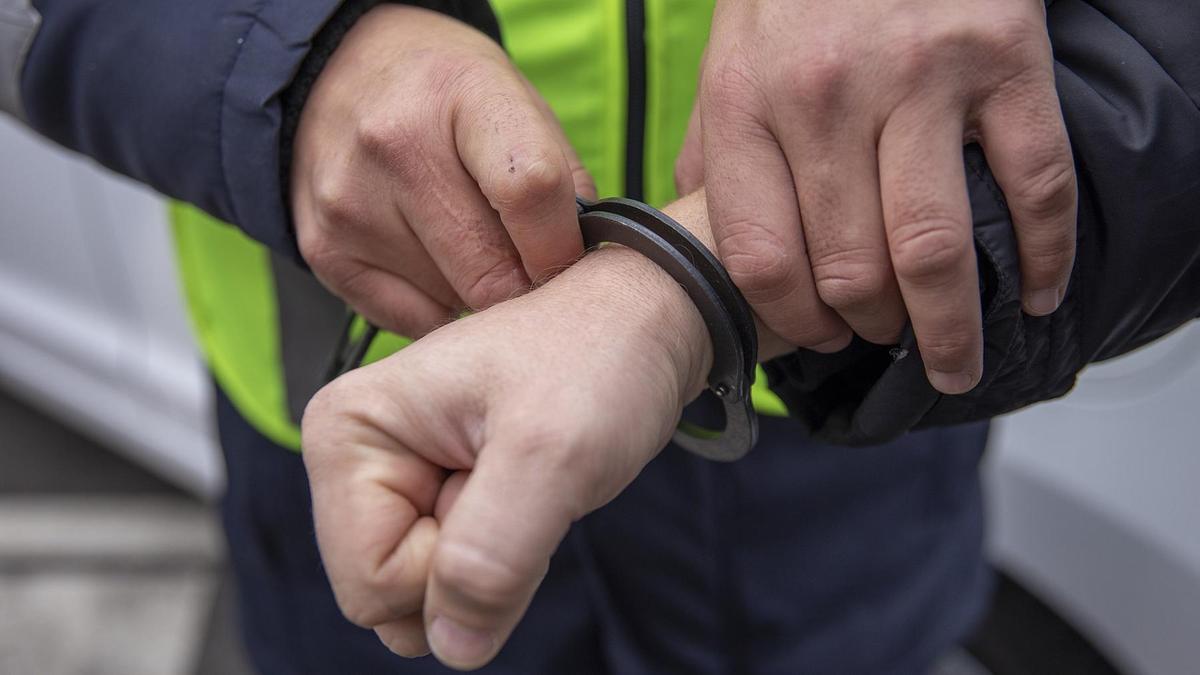Полицейский одевает наручники на задержанного Полицейский одевает наручники на задержанного