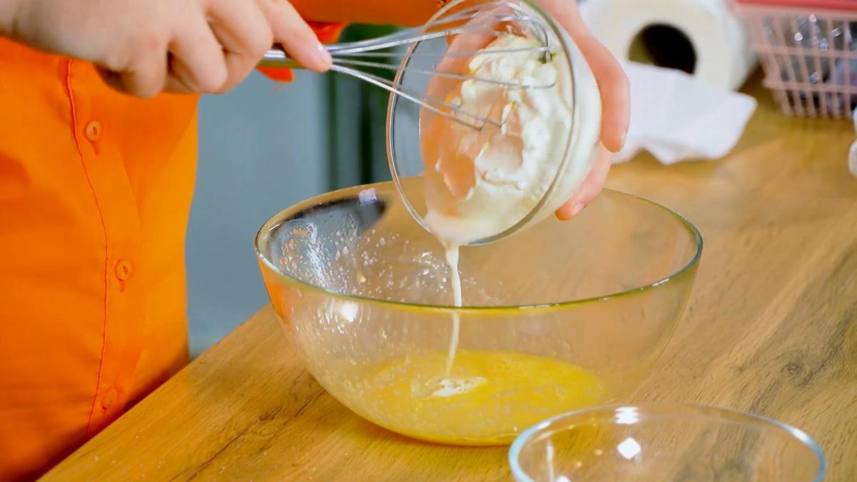 Сметану из стеклянной пиалы перекладывают в миску с яичной массой