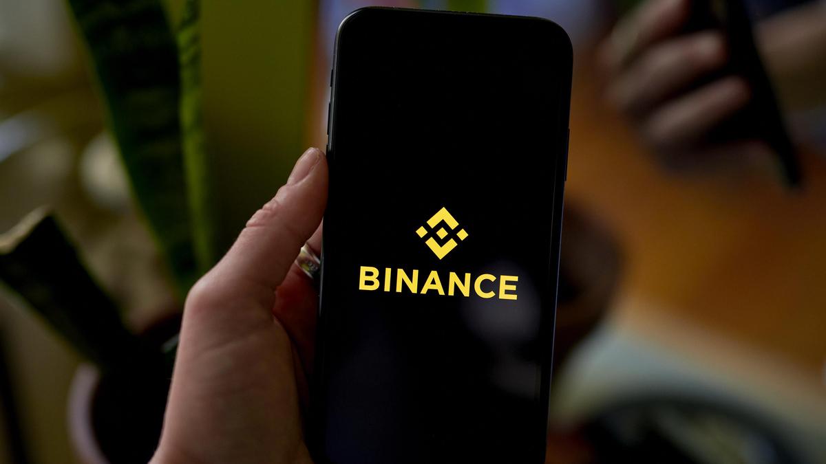 Человек держит смартфон с приложением Binance