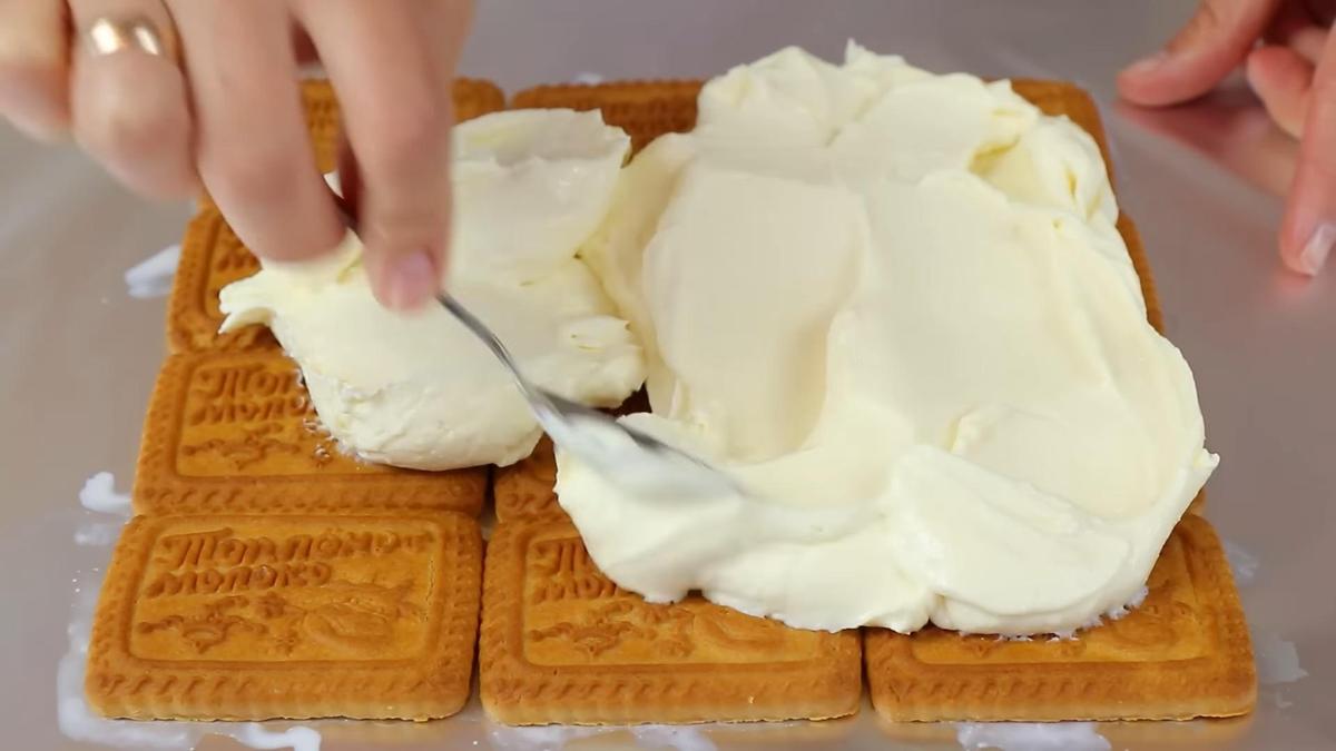Творожный крем выкладывают ложкой на основу из печенья