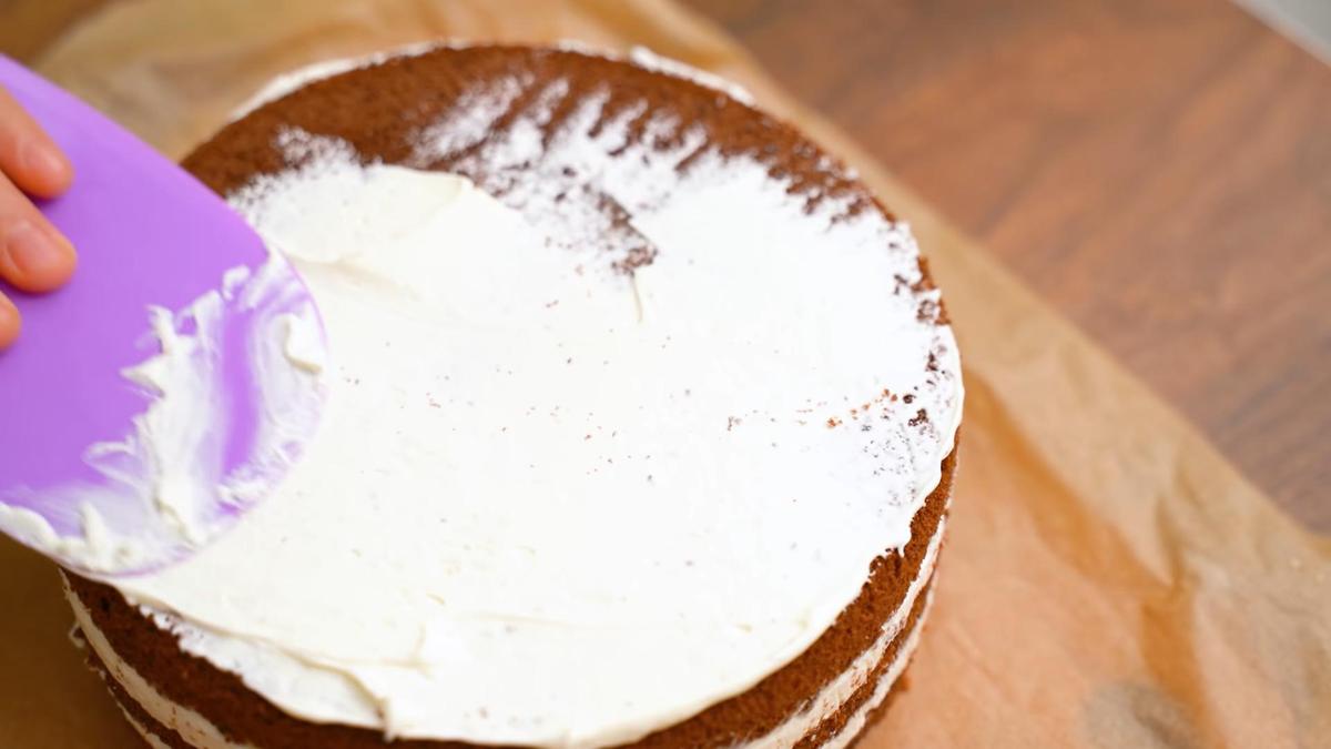 Торт «Сникерс» покрывают сливочным кремом