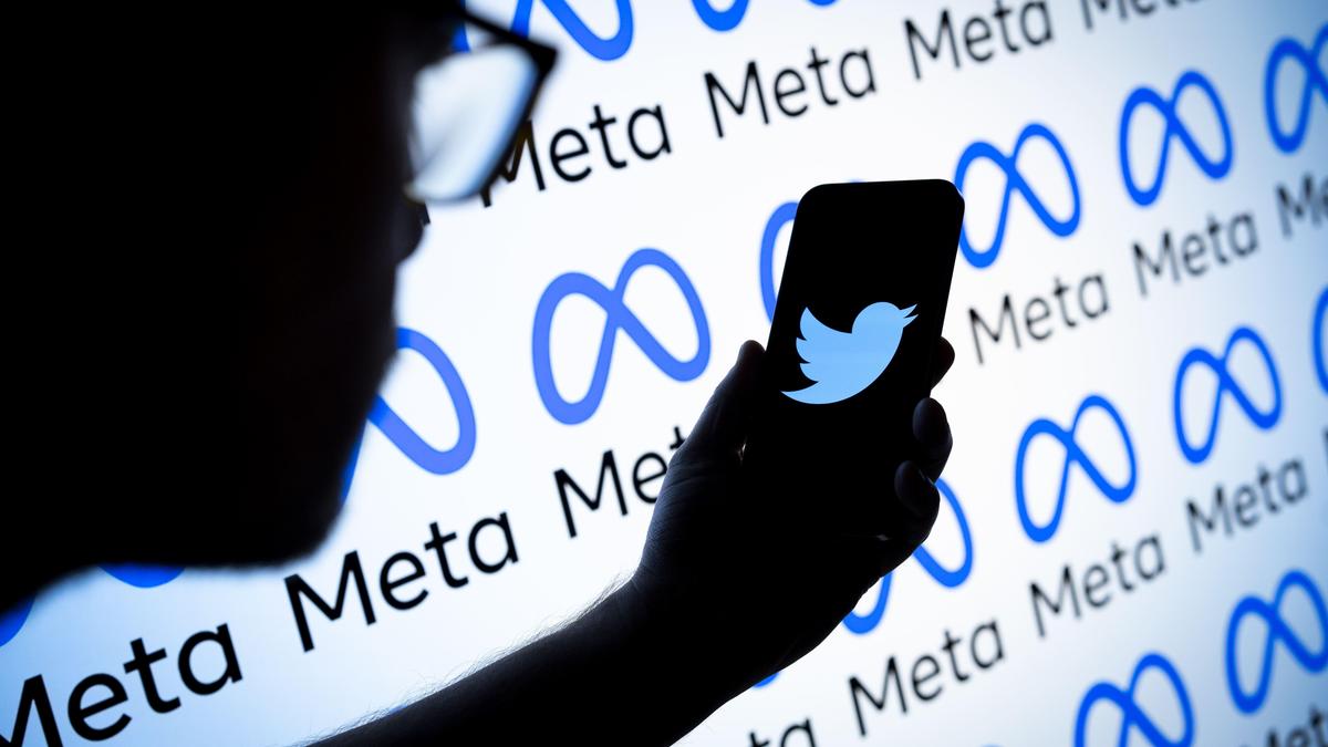 Человек держит телефон с логотипом Twitter на фоне Meta