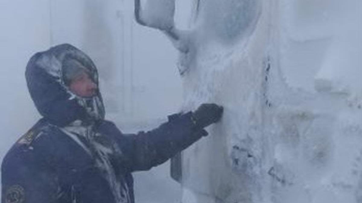 Мужчина в буран стоит на лице возле машины