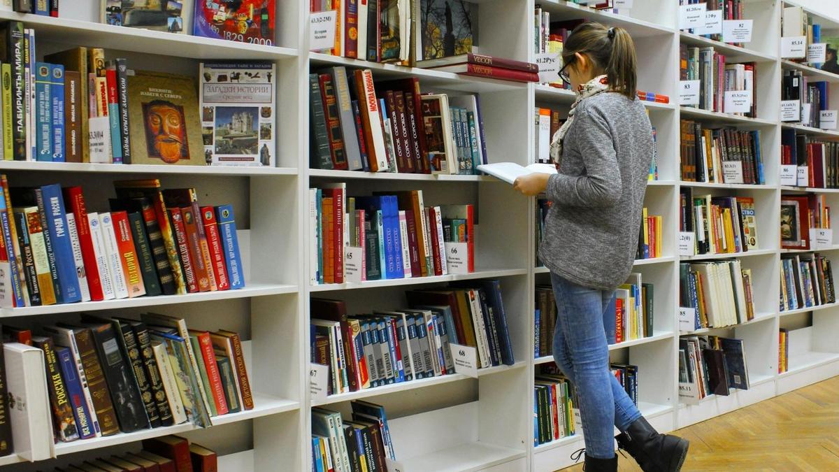 Студентка читает книгу в библиотеке