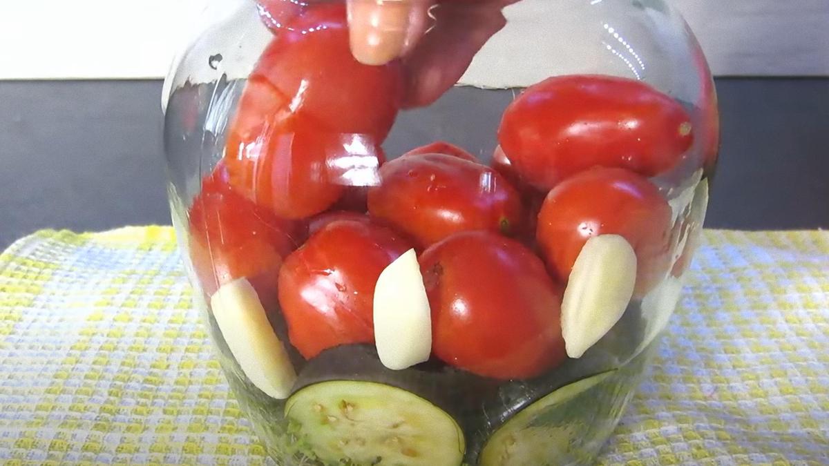 В банку укладывают кусочки баклажана и целые помидоры