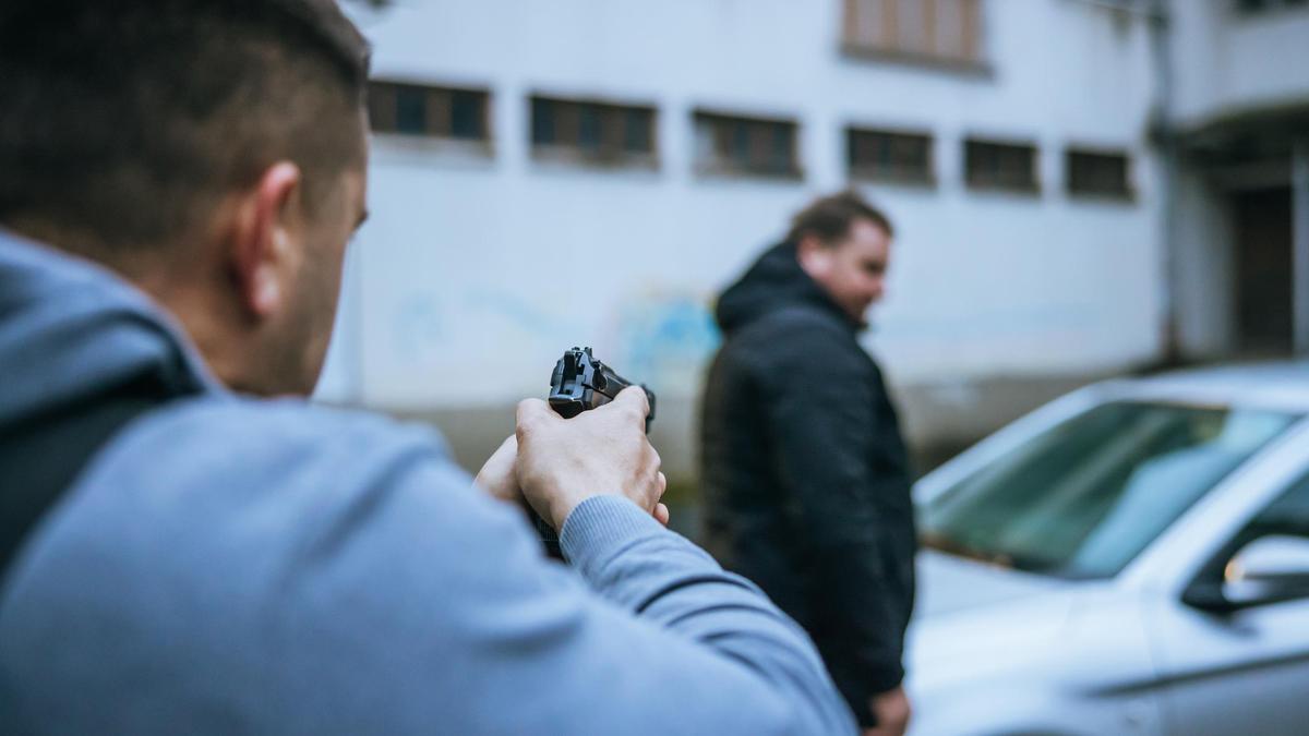 Мужчина целится из пистолета в жертву Мужчина целится из пистолета в жертву