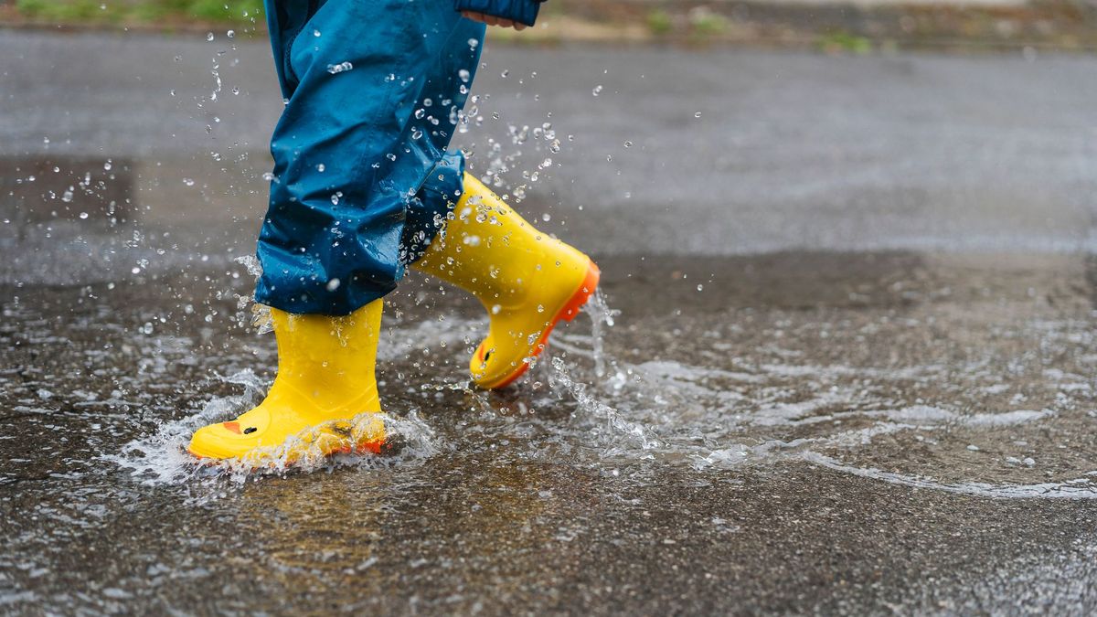 Ребенок в резиновых сапогах ходит по лужам