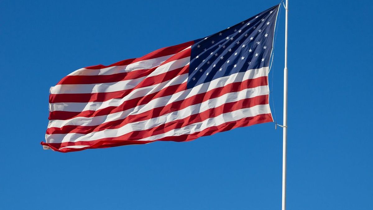Флаг США развивается на ветру на фоне ясного неба