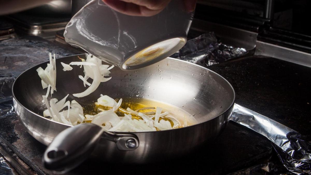На сковороду насыпают нарезанный перьями лук
