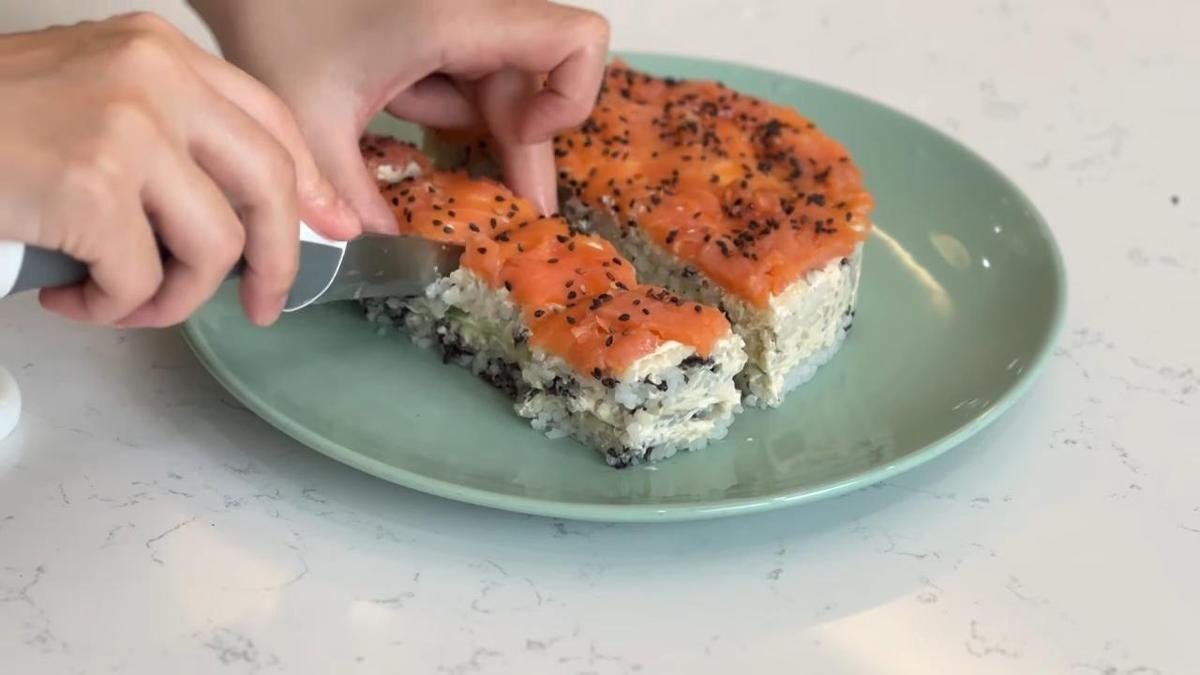 На сервировочной тарелке нарезают суши-салат