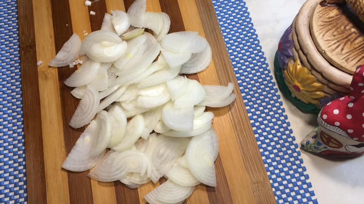 Нарезанный полукольцами репчатый лук на разделочной доске