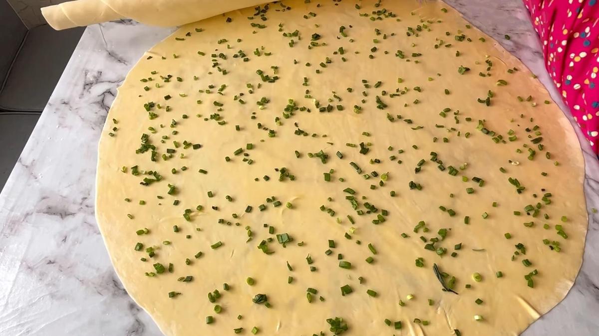 На столе раскатанное тесто с луком