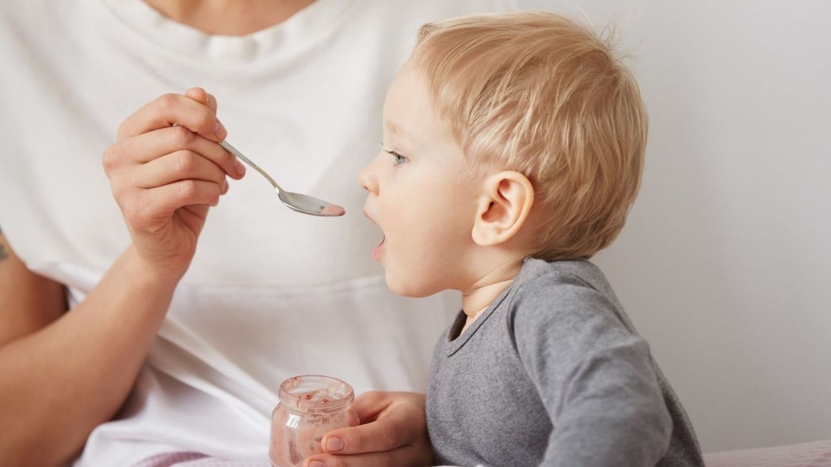 Мама кормит ребенка с ложки