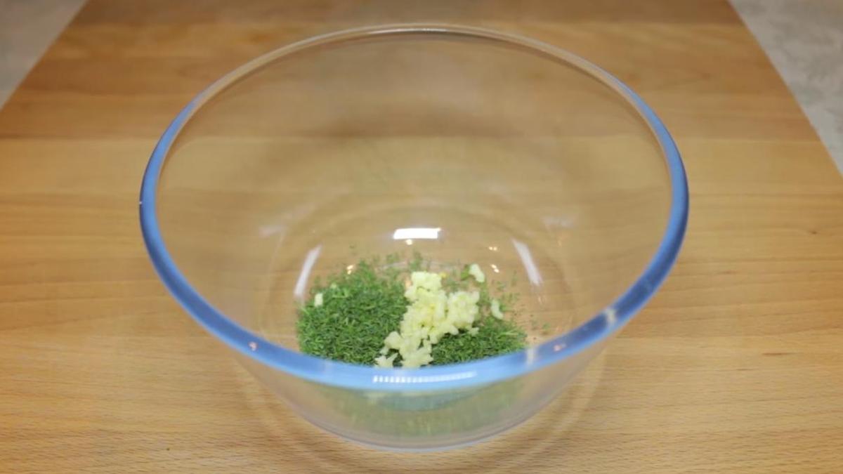 Измельченый чеснок в миске с укропом